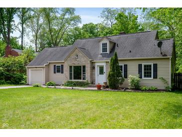 Charming home featuring a manicured lawn and stone detailing around the front picture window at 7910 N College Ave, Indianapolis, IN 46240