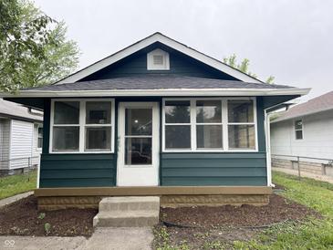 Charming home with a dark green exterior and a sunny, glass enclosed, front porch at 946 N Somerset Ave, Indianapolis, IN 46222