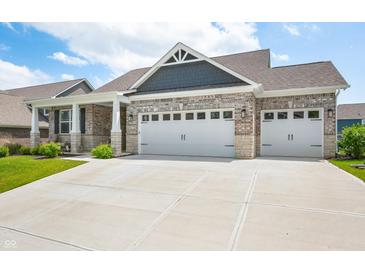 Lovely exterior features a three car garage, stone accents, brick, and well-maintained landscaping at 963 Booneway Ln, Bargersville, IN 46106