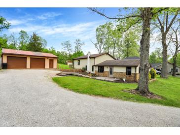 Charming home exterior with a spacious yard, detached garage, and gravel driveway at 10972 W Old Nashville Rd, Columbus, IN 47201