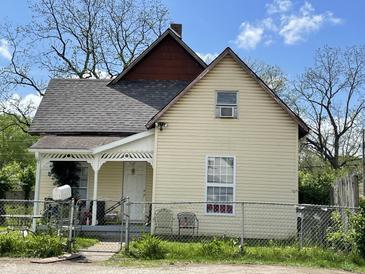 Charming two-story home featuring a welcoming porch and a well-maintained, fenced yard under a bright blue sky at 1164 Groff Ave, Indianapolis, IN 46222