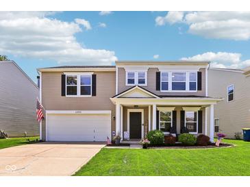 Charming two-story home with well-manicured lawn, lovely landscaping, covered front porch, and attached two-car garage at 12993 E 131St St, Fishers, IN 46037