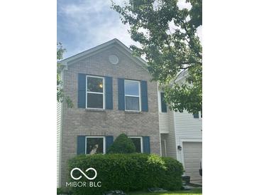 Charming two-story home with light brick, dark shutters and well-manicured landscaping at 10746 Raven Ct, Fishers, IN 46038