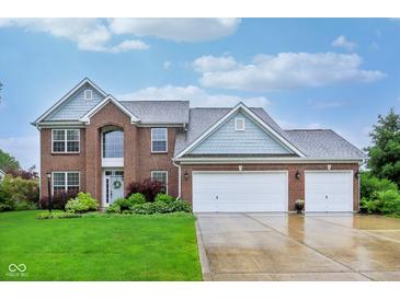 Stunning two-story brick home featuring a three-car garage and well-manicured front lawn with landscaping at 13145 Roma Bnd, Carmel, IN 46074