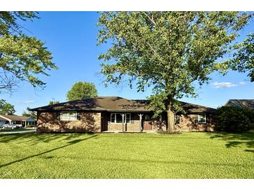 Charming brick home featuring a spacious front yard and beautiful mature trees on a sunny day at 1328 N 300 E, Anderson, IN 46012