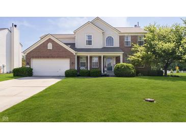 Charming two-story home featuring brick and siding exterior, manicured lawn and mature trees at 14135 Nicholas Dr, Carmel, IN 46074
