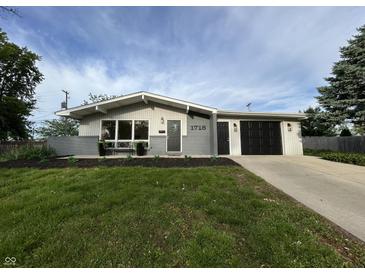 Charming single-story home featuring a well-manicured lawn, attached garage, and modern exterior paint at 1718 South Dr, Columbus, IN 47203