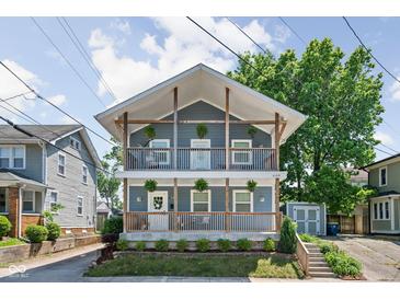 Charming two-story home featuring dual balconies, light blue siding, and a well-manicured front yard at 609 E 39Th St, Indianapolis, IN 46205