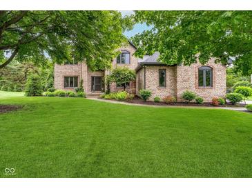 Beautiful brick home featuring a lush green lawn and mature trees providing shade at 12563 Sandstone Run, Carmel, IN 46033