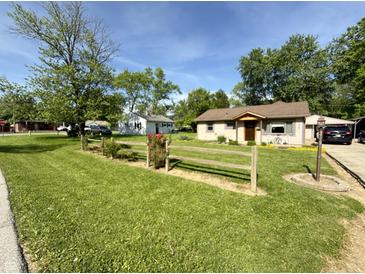Charming single-Gathering home with a well-maintained lawn, a split rail fence, and mature shade trees at 309 Arlington Dr, Whiteland, IN 46184