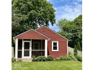Charming red cottage with a screened-in porch, green lawn, and surrounded by mature trees at 4714 Crestview Ave, Indianapolis, IN 46205