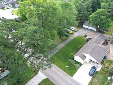 An aerial view of a home with a lush green lawn, mature trees, and a long driveway leading to a detached garage at 71 W County Road 500 S, Clayton, IN 46118