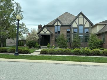 Inviting brick two-story home boasts Tudor accents, tall windows and well-manicured front lawn at 7661 Carriage House Way, Zionsville, IN 46077