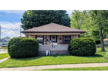 Charming single-story home with a welcoming front porch, beautiful lawn, and lush greenery at 100 N 6Th Ave, Beech Grove, IN 46107