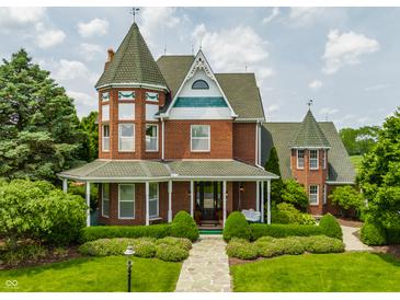 Beautiful Victorian home featuring manicured landscaping, brick facade, and charming front porch with swing at 11705 N Shelby 700 W, New Palestine, IN 46163