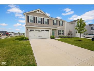 Two-story home featuring a two-car garage, tan siding, black shutters and a well-maintained green lawn with a long driveway at 13887 N Hawkers Hill Dr, Camby, IN 46113