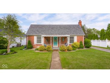 Charming brick home featuring a well-manicured lawn and inviting front porch with a swing at 2021 Chestnut St, Columbus, IN 47201