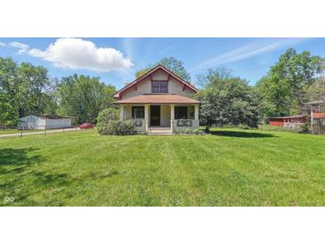 Charming two-story home features a cozy front porch and a well-manicured lawn on a sunny day at 102 N Whitcomb Ave, Indianapolis, IN 46224
