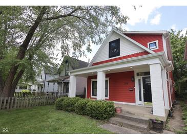 Charming red two-story home featuring a covered front porch with white columns and manicured landscaping at 1156 Spruce St, Indianapolis, IN 46203