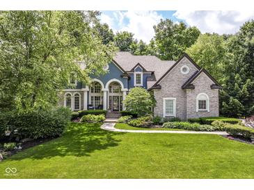 Beautiful two-story home with a well-manicured lawn, mature trees, and striking architectural details at 13017 Water Ridge Dr, McCordsville, IN 46055