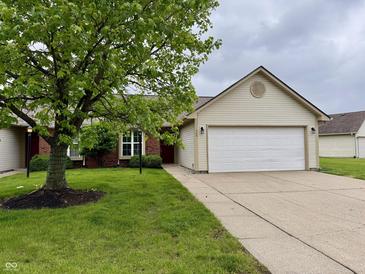 Charming home featuring an attached two-car garage, brick facade, manicured lawn and mature shade tree at 509 Woodberry Dr, Danville, IN 46122