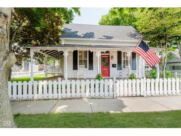 Charming home featuring a covered porch with swing, white picket fence, and American flag at 60 E Poplar St, Zionsville, IN 46077