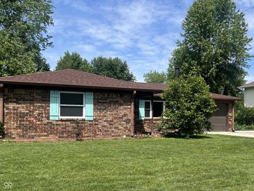 Brick home with beautiful lawn and landscaping features a brown roof and blue shutters at 7824 Hearthstone Way, Indianapolis, IN 46227