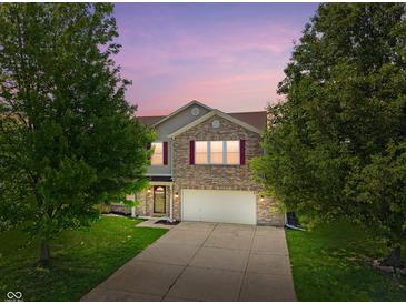 Charming two-story brick home with a well-manicured lawn and attached two-car garage at dusk at 8631 Belle Union Pl, Indianapolis, IN 46113