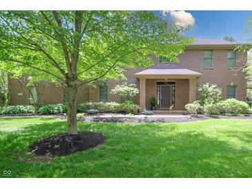 Charming brick home featuring a well-manicured lawn and a mature tree in the front yard at 876 Box Turtle Ct, Columbus, IN 47201