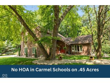 Charming two-story brick home with a landscaped yard and mature trees, offering a serene and private setting at 3479 Sugar Loaf Ct, Carmel, IN 46033