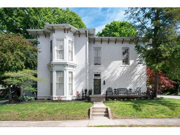 Charming white home featuring a bay window, front porch with seating, and well-manicured lawn at 8 W Jackson St, Knightstown, IN 46148