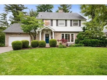 Charming two-story home with a well-manicured lawn and landscaped yard featuring mature trees and manicured shrubbery at 6020 Gladden Dr, Indianapolis, IN 46220