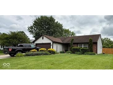 Charming home with a well-manicured lawn, mature landscaping, and a driveway featuring a black truck at 8123 Summertree Ct, Indianapolis, IN 46256