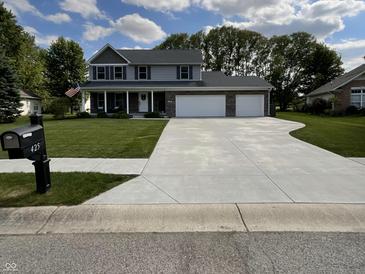Exterior of two-story home featuring a large lawn, brick facade, and a three-car garage at 425 Bridgewater S Ln, Muncie, IN 47304