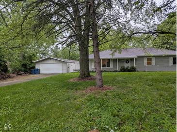 Charming single-story home with a detached garage and a beautiful, spacious front yard featuring mature trees at 5160 N High School Rd, Indianapolis, IN 46254