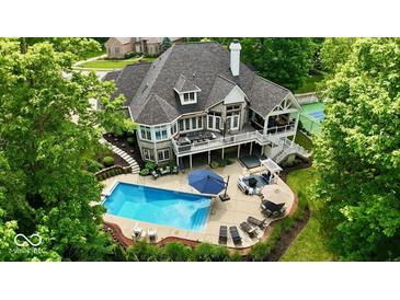 Expansive home with a backyard oasis featuring a pool, hot tub, tennis court, and multiple seating areas at 7016 Royal Oakland Way, Indianapolis, IN 46236