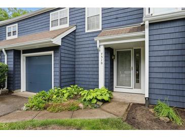 Inviting townhouse with a blue exterior, well-kept landscaping, and attached garage at 7510 Harbour, Indianapolis, IN 46240