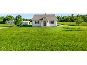 Charming one-story house featuring a well-maintained lawn, an exterior propane tank, and supplemental storage structures at 10758 W State Road 142, Quincy, IN 47456