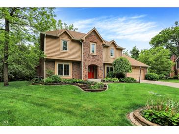 Charming two-story home featuring a brick facade, well-manicured lawn, and a bright red front door at 11469 Woodview Ct, Fishers, IN 46038