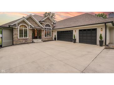 Beautiful stone and siding home featuring a spacious driveway and a three-car garage at 11911 W Grandview Dr, Columbus, IN 47201