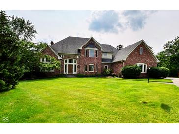 Stately brick home features an expansive green lawn, mature trees, and an inviting front entrance at 12854 Northants Cir, Carmel, IN 46032
