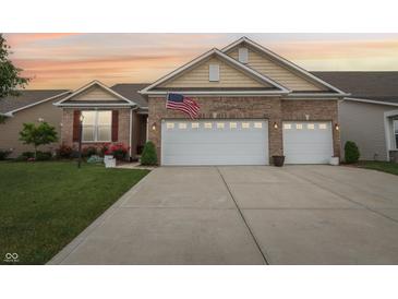 Charming brick home featuring an attached two car garage, manicured lawn, and an American flag at 1468 Blackthorne N Trl, Plainfield, IN 46168