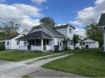 Charming two-story home featuring a front porch, well-maintained lawn, and a separate garage at 207 E Plum St, Anderson, IN 46012