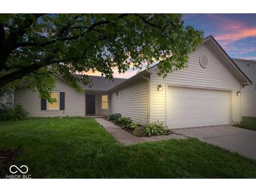 Charming single-story home featuring a two-car garage, well-kept lawn, and tasteful landscaping at sunset at 6011 Twyckenham Dr, Indianapolis, IN 46236