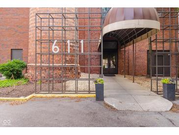 Brick building entrance with a covered walkway and decorative iron number display; planter boxes flank the entrance at 611 N Park Ave # 108, Indianapolis, IN 46204