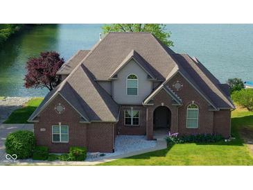 Charming brick two-story home features a well-maintained lawn and stunning waterfront views, ideal for serene lakeside living at 719 E New Rd, Greenfield, IN 46140