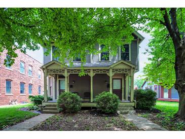 Charming two-story home featuring a covered porch and landscaped front yard with mature trees at 925 Fayette St, Indianapolis, IN 46202