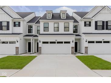 A townhome with white siding, black accents, and a two car garage, showcasing modern curb appeal at 9741 Oleander Dr, Fishers, IN 46250