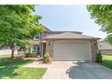 Charming two-story brick home with a well-maintained lawn and mature trees under a clear sky at 977 Canary Creek Dr, Franklin, IN 46131