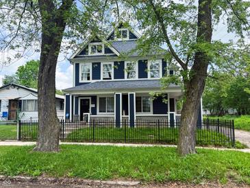 Charming two-story blue home with white trim, well-manicured lawn and black metal fence at 201 N Tacoma Ave, Indianapolis, IN 46201
